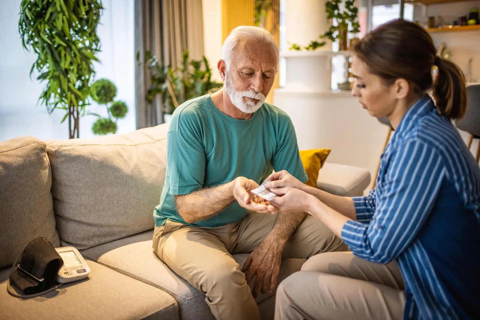An older man smiling on the couch with his caregiver